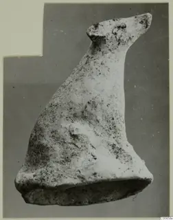 Terracotta figurine of an animal with a long raised neck, small pointed head and flat base, against a grey backdrop