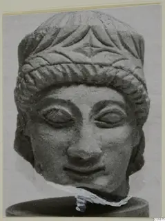 Limestone sculpture head from Mersinaki, front view, with a carved face, incised hair band and broken neck