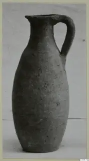 Single-handled jug of coarse pottery with a narrow neck, photographed upright on a plain background