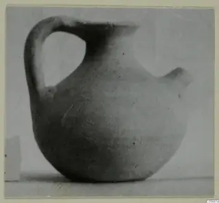 Plain pottery jug with a strap handle and a spout, photographed against a plain background.