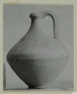 Plain pottery jug with a single strap handle, shown against a plain grey backdrop.