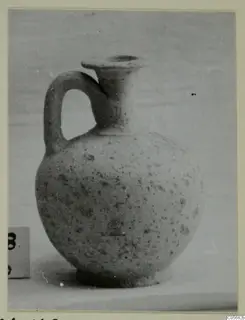 Pottery jug with a single loop handle and a flared rim, shown on a plain surface beside a number label.
