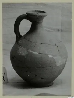 Pottery Plain White VII jug from Marion with one handle, cracked and partly restored, against a plain background.