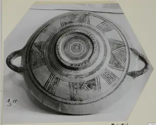 Round pottery vessel with two loop handles, seen from above, decorated with concentric rings and radiating painted motifs.