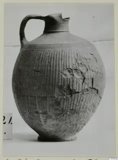 Foreign Red Slip jug with a strap handle, pinched spout and vertically ribbed body