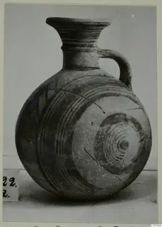 Round-bodied jug with a flared neck and a single loop handle, decorated with concentric painted circles.