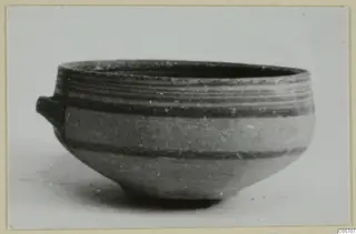 Pottery bowl from Amathus with a small lug handle and dark horizontal bands, seen from the side.