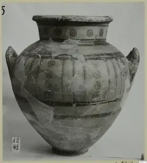 Pottery Black-on-Red amphora from Amathus with concentric circles and vertical bands, photographed against a grey backdrop