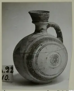 Round-bodied jug with a flaring neck, single loop handle and painted bands, photographed on a plain background