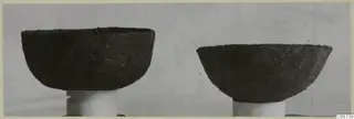 Two dark bowls from Marion Tomb 97, each standing on a white cylindrical support.