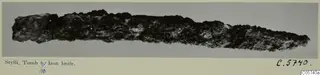 Corroded iron knife from Stylli, Tomb 6/10, shown horizontally against a grey background