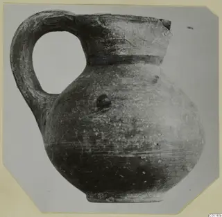 Pottery Black-on-Red II-IV juglet with a loop handle and a broken rim