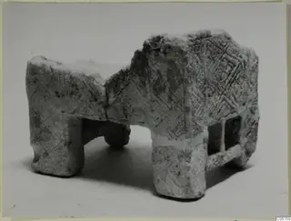 Pale stone object with incised diamond patterns, four squared legs and openings in its side, from Marion