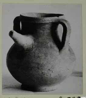 Round pottery vessel with two handles and a short spout, shown on a photo mount with a Cypro-Hell label