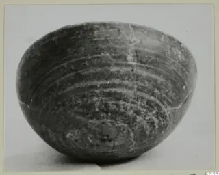 Foreign Red Slip bowl with concentric banded decoration around its rounded body, seen from the side