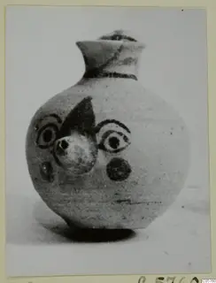 Round jug with a flaring neck and dark painted motifs, including concentric circles and a dark triangle