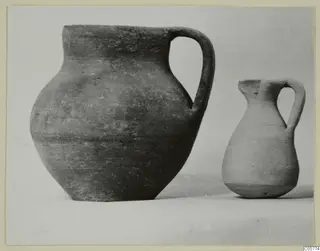 Two pottery jugs with single strap handles, photographed side by side against a plain background.