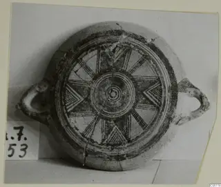 Plate with two loop handles, its interior painted with concentric rings, radiating spokes and chevrons in dark paint