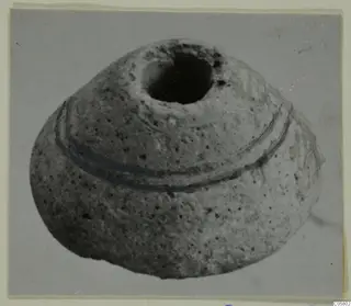 Rounded, squat object with a wide dark opening at the top and two dark bands encircling its body, photographed on a grey background.