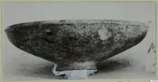 Black Slip bowl with a low foot, shown in side view on a pale support