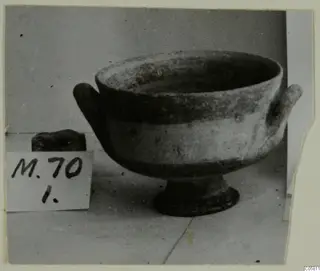 White Painted I bowl with two horizontal handles and a ring foot, shown beside a handwritten number label