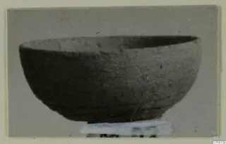 Pottery Plain White VI bowl seen from the side, standing on a pale paper label at its base