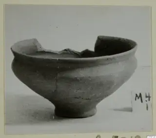 Pottery bowl with a broken rim, find from Marion, photographed alone on a pale surface