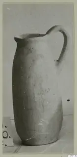Tall jug with a single strap handle and a pinched spout, shown on a plain backdrop.