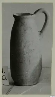 Plain pottery jug with a single loop handle and a trefoil-like pouring lip, shown on a plain surface.
