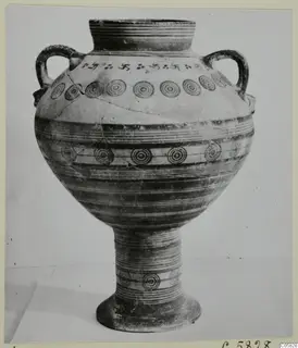 White Painted V pottery stand-vessel with two handles, concentric circle and swastika-like painted motifs.