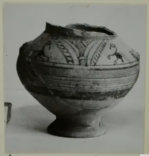 Pottery Bichrome V vessel with a round body, high foot and dark painted bands and motifs, photographed on a pale surface