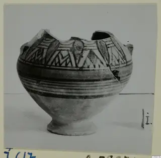 Pottery Bichrome IV amphora-crater with a broken rim, decorated with dark bands and angular patterns on a pale body.