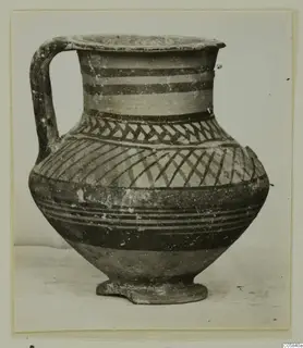 Pottery Bichrome V jug with a single handle, painted with dark bands and hatched patterns