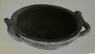 Shallow grey pottery bowl with two small handles on opposite sides, photographed on a pale backdrop.