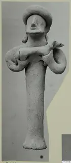 Terracotta statuette of a standing figure with a wide rounded headdress and arms bent outward, holding a small animal across its body.