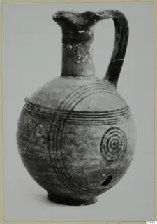 Round-bodied jug with a tall neck and loop handle, decorated with dark concentric circles and bands.