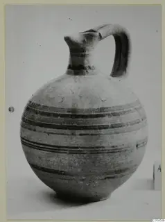 Pottery Bichrome V jug with a tall neck, strap handle and dark painted bands around the body