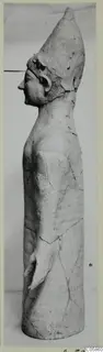 Terracotta standing figure from Mersinaki, shown in profile facing left, with a tall conical headdress.