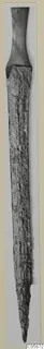 Iron sword with a long, corroded blade and a dark handle at the top, photographed upright on a pale card mount.