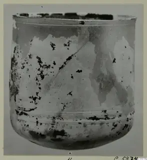 Blown glass vessel from Idalion, cylindrical with a flared rim and a rounded base, with a weathered surface.