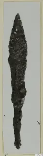 Corroded iron blade with a pointed tip, shown upright on a light card mount
