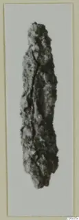 Corroded iron weapon, long and narrow with a pointed end, against a pale background.