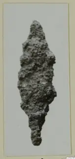 Corroded iron weapon with a pointed, leaf-shaped blade and a narrow tang, photographed on a card mount
