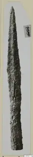 Iron weapon with a long pointed blade, its surface rough and corroded, shown upright on a card mount