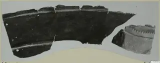 Two bronze weapon fragments: a large curved piece with small holes near its edge and a smaller piece with a notched rim.