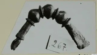 Bronze fibula with an arched bow and three rounded knobs, shown on a pale card mount
