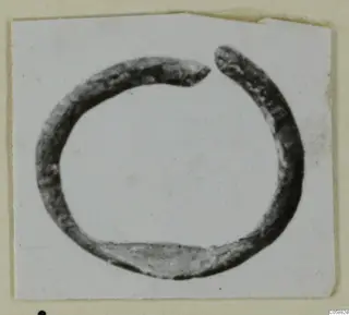 Open bronze ring with a gap at the top, photographed on a card mount.