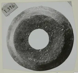 Ring-shaped metal object with a large central hole and a corroded, pitted surface.
