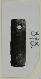 Cylindrical bronze fragment with a round hole near one end, photographed on a card