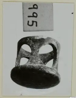 Bronze openwork mounting with a flat disc base and round openings in its sides, photographed against a light background.